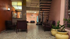 Um hall com piso de azulejos, cadeiras de madeira e plantas em vasos.