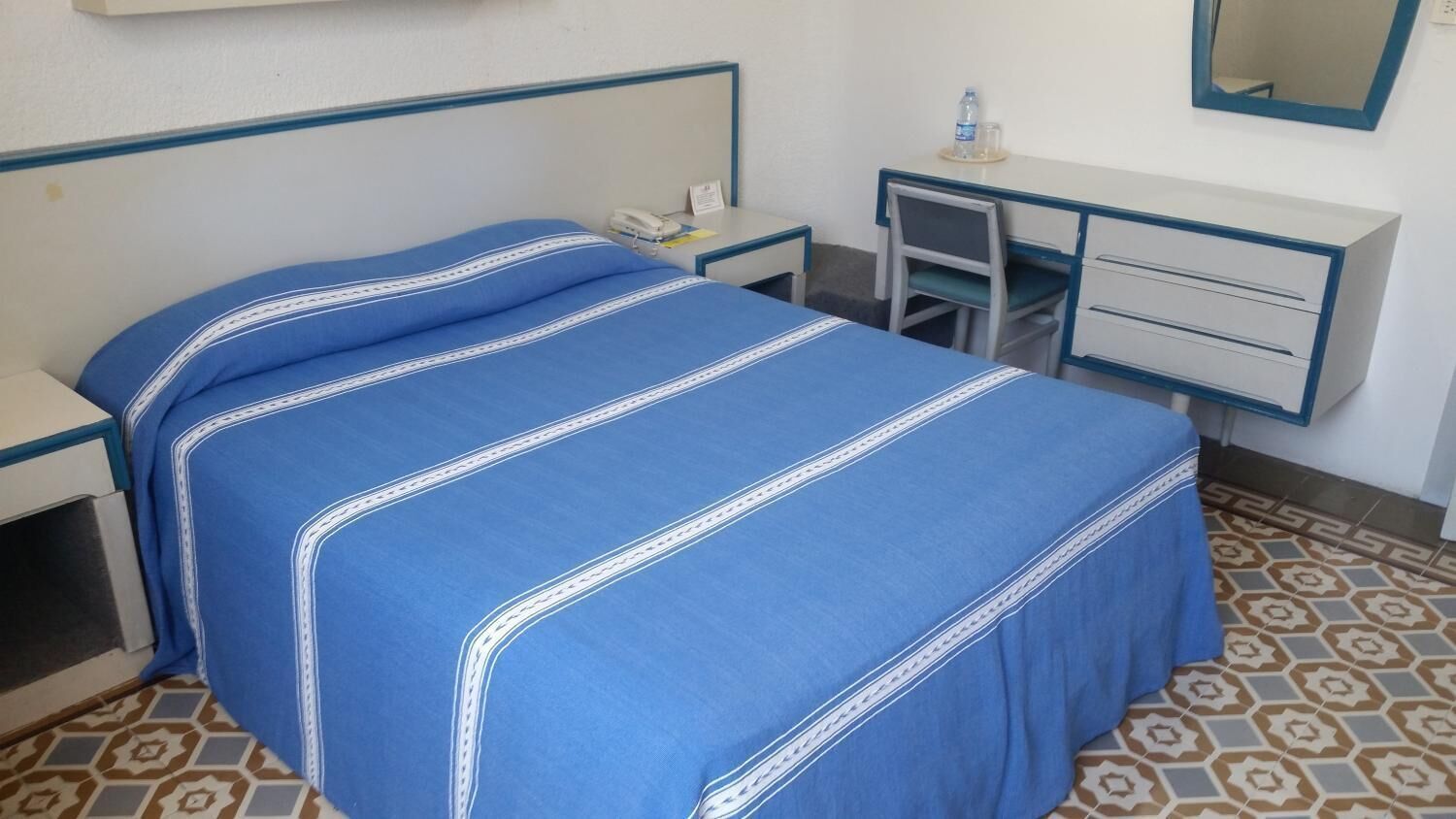 Une chambre d’hôtel avec un lit, un bureau, une chaise et une petite table.