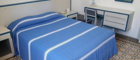 Une chambre d’hôtel avec un lit, un bureau, une chaise et une petite table.