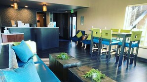 A modern lobby with a reception desk, seating area with sofas and chairs, and a staircase in the background. - The Hotel Y, a Dazzler Select by Wyndham (Yakima)