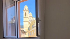 A room with a large window overlooking a building with a bell tower. - Beautiful Apartment ! Historic District Bastia (Bastia)