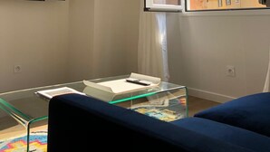 A modern living room with a large window, a flat-screen TV, and a glass coffee table. - Beautiful Apartment ! Historic District Bastia (Bastia)