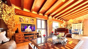 A cozy living room with a wooden ceiling, a television, a fireplace, and a dining area. - Villa CALIMA in Benissa – 3 bedrooms, private pool, sea and mountain views, Wi-Fi and private parking (Benissa)