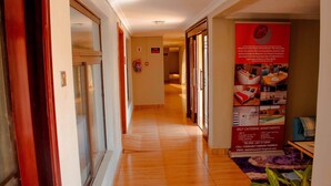 Corredor de hotel com piso de madeira, um extintor de incêndio e um aviso de apartamentos com cozinha.