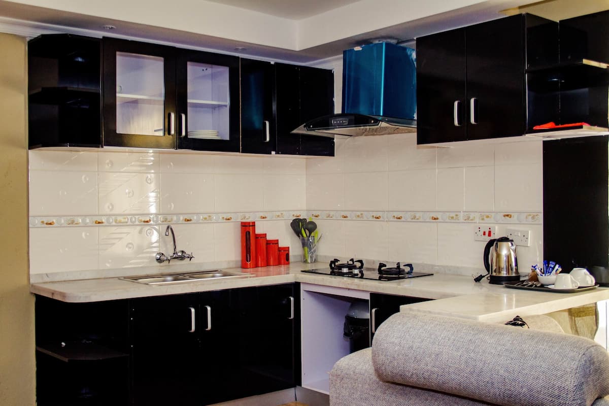 A compact kitchen with black cabinets, a white countertop, and a built-in stove.