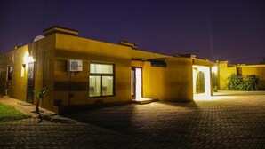 Um edifício com fachada amarela, uma porta visível e um aparelho de ar condicionado.