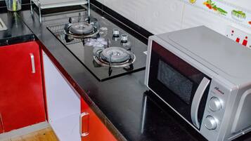 A kitchen with a gas stove, a microwave, and red cabinets.