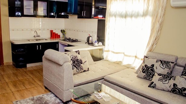 Um espaço compacto com cozinha compacta, um conjunto de sofás e uma mesa de centro de vidro.
