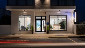 A modern hotel entrance with glass doors, potted plants, and a visible staircase leading to the upper floor. - Hotel Costa da Morte (Fisterra)