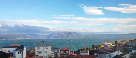 A coastal town with buildings, a body of water, and mountains in the background.