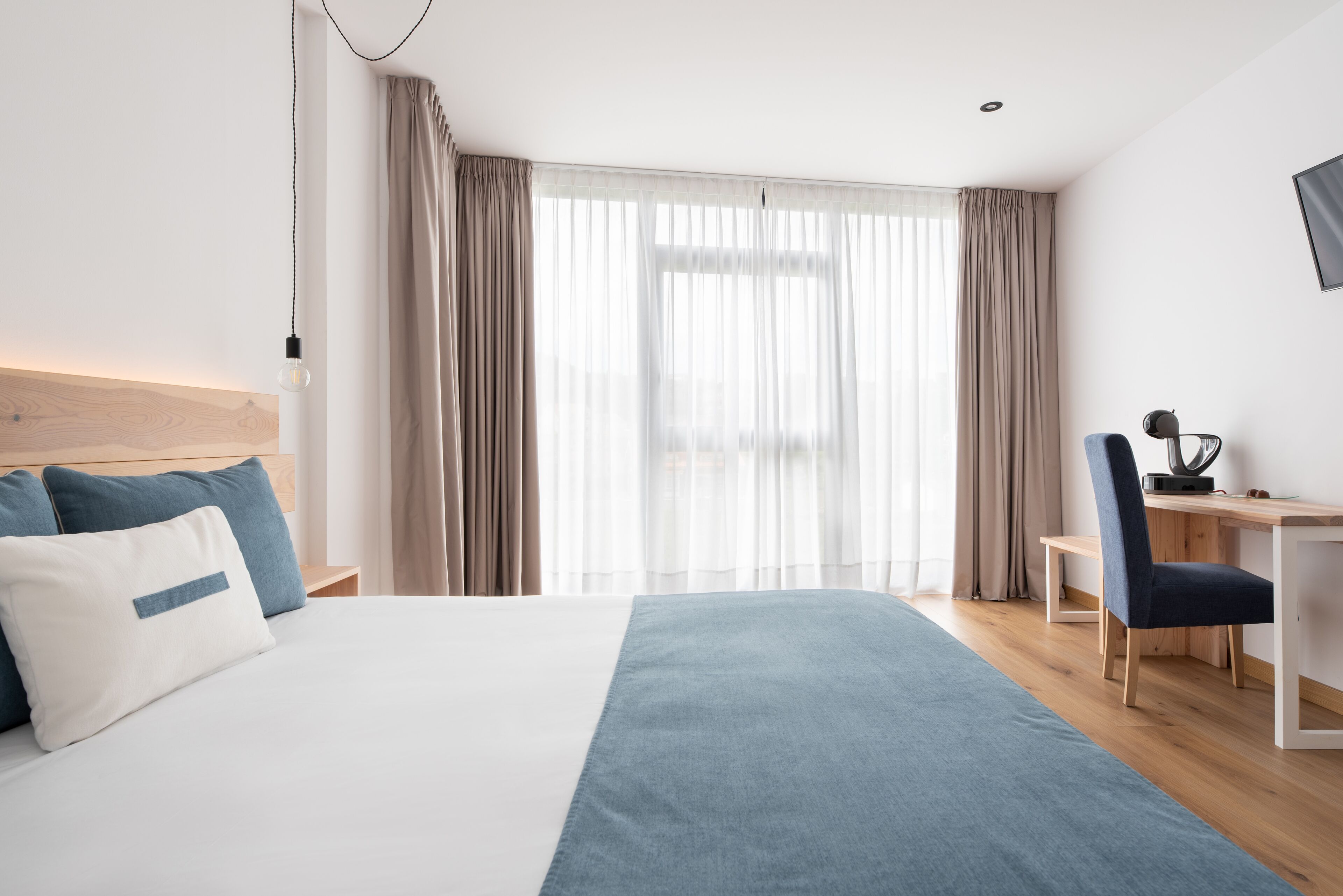 Habitación de hotel moderna con una cama grande, un escritorio y una silla.
