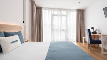 Habitación de hotel moderna con una cama grande, un escritorio y una silla.
