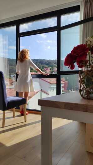 Una persona de pie junto a un ventanal grande con vistas a una zona residencial.