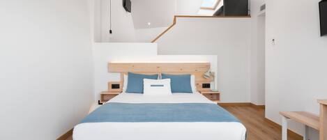 Une chambre moderne avec un lit en bois, des murs blancs et une lucarne.