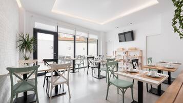 Un comedor moderno con paredes de ladrillo blanco, ventanas amplias y un televisor de pantalla plana montado en la pared.