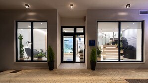 A modern hotel entrance with glass doors, potted plants, and a visible reception area. - Hotel Costa da Morte (Fisterra)
