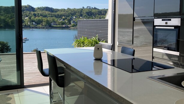 Una cocina moderna con una isla grande, vistas a un lago y un comedor con sillas.