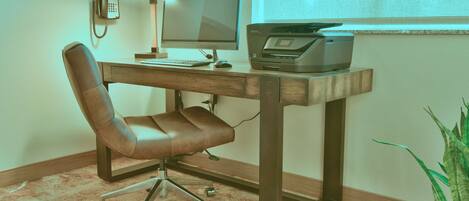 A wooden desk with a computer, a printer, and a phone.