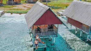 A bungalow-style resort with a water view, featuring a wooden deck and a covered porch. - Private Over the Water Cabin on San Blas Island (Las Huacas)