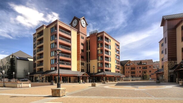 A multi-story hotel with a central clock tower, outdoor seating areas, and a paved plaza. - 04505_p9 (Breckenridge)