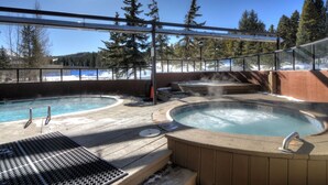 A hot tub area with a pool, surrounded by a glass enclosure, and a view of snow-covered ground and trees. - 04505_p9 (Breckenridge)