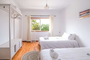 Une chambre avec deux lits, une fenêtre avec des rideaux, une échelle et un luminaire suspendu.