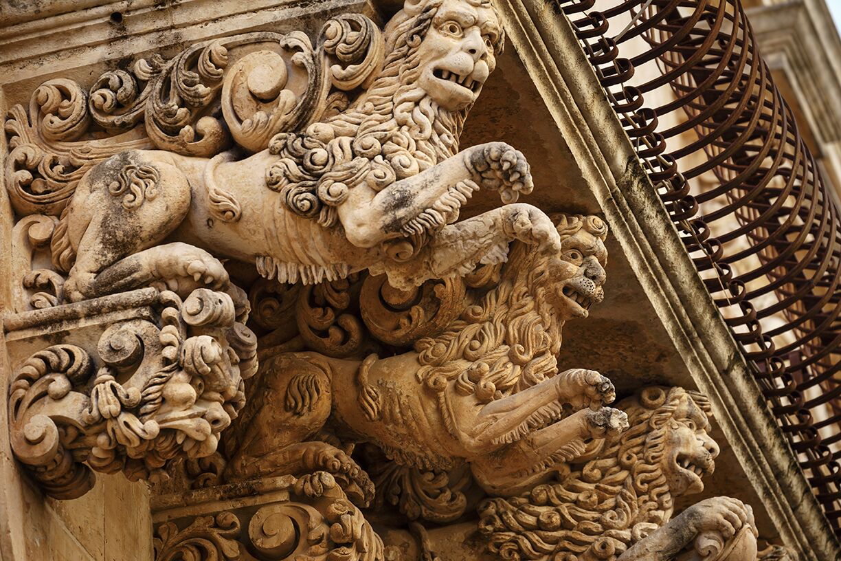 Une sculpture détaillée dans la pierre représentant un lion, ornée de motifs complexes.