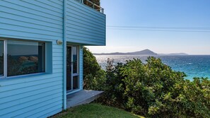 A light blue building with a view of the sea and a distant mountain.