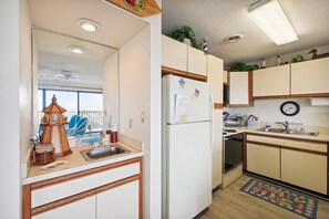Eine Küche mit Kühlschrank, Spüle und Holzschränken.