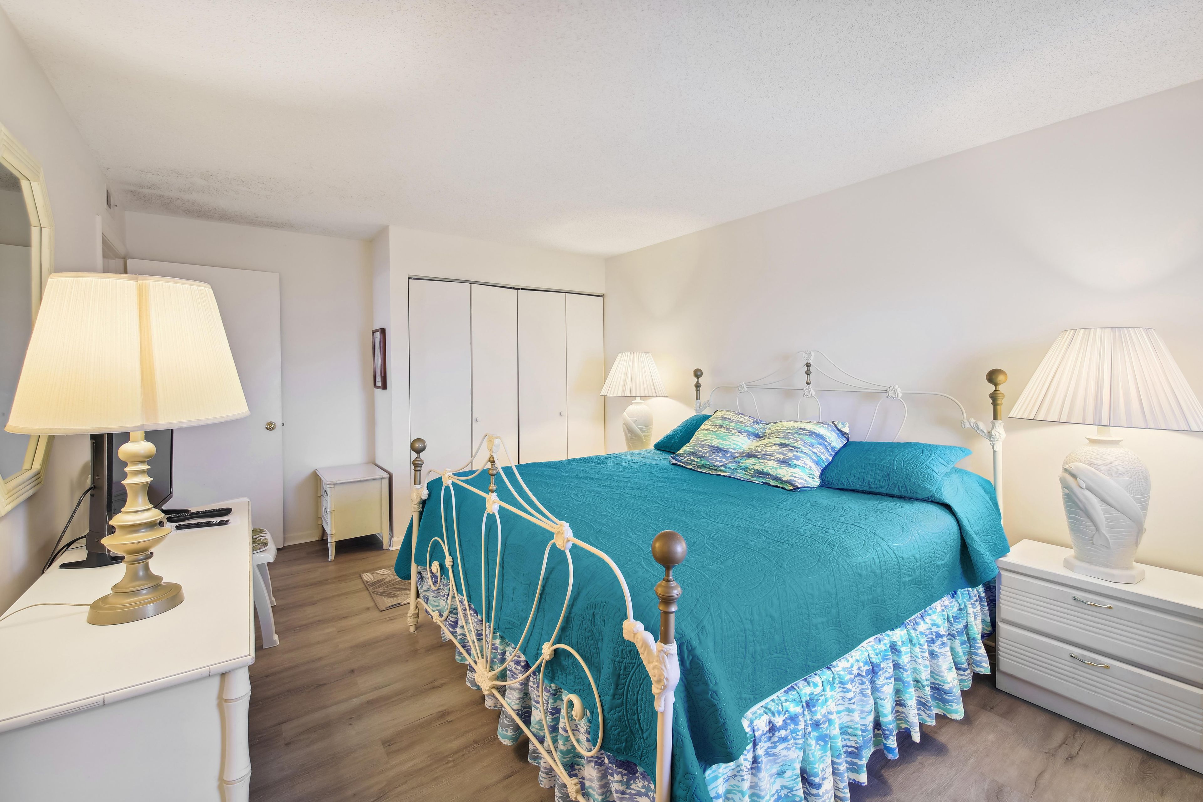 A bedroom with a bed, bedside tables, lamps, and a wardrobe.