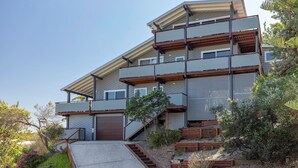 Uma casa moderna de vários andares com garagem, varanda coberta e escada que leva aos níveis superiores.