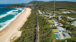 Vista aérea de uma área residencial costeira com praia, casas e uma estrada.