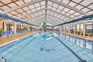 Ein Innenpool mit blauen Liegestühlen und Pflanzen rundherum.