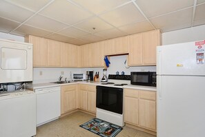 A compact kitchen with white appliances, wooden cabinets, and a tiled ceiling. - LINENS & DAILY ACTIVITIES INCLUDED*!!! THE CAPRI - 2BR/2BA condo with ocean & bay views. Indoor pool and many building amenties! (Ocean City)