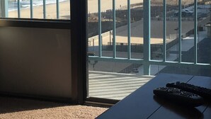 Ein Zimmer mit Blick auf den Strand, ein Balkon mit Metallgeländern und ein Tisch mit Fernbedienung.