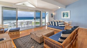 A spacious living area with a large sliding glass door leading to a balcony overlooking the ocean. - Blue Pacific - Pacific Palms Holidays (Boomerang Beach)