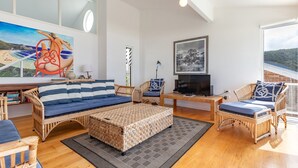A spacious living room with wicker furniture, a television, and artwork on the walls.