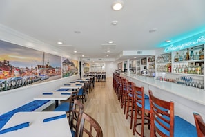 A bar area with a neon sign reading "Chesapeake Bay" and a mural of a cityscape on the wall. - XPLORIE ACTIVITIES & LINENS INCLUDED*! THE PLAZA - Spacious 3BR/2BA condo located on the 8th floor. Indoor/outdoor pools & Tiki Bar! (Ocean City)