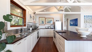 A modern kitchen with white cabinetry, a wooden countertop, and a large island with a bowl. - Barefoot on Blueys - Blueys Beach (Blueys Beach)