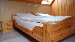 A wooden bed with a slatted headboard, a nightstand with drawers, and a skylight above. - Apartment morning sun (Pruchten)