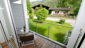 A balcony with a view of a mountain landscape, a wooden table with a chair, and a glass door. - Apartment Glacier View 14.2 with balcony (Kaprun)