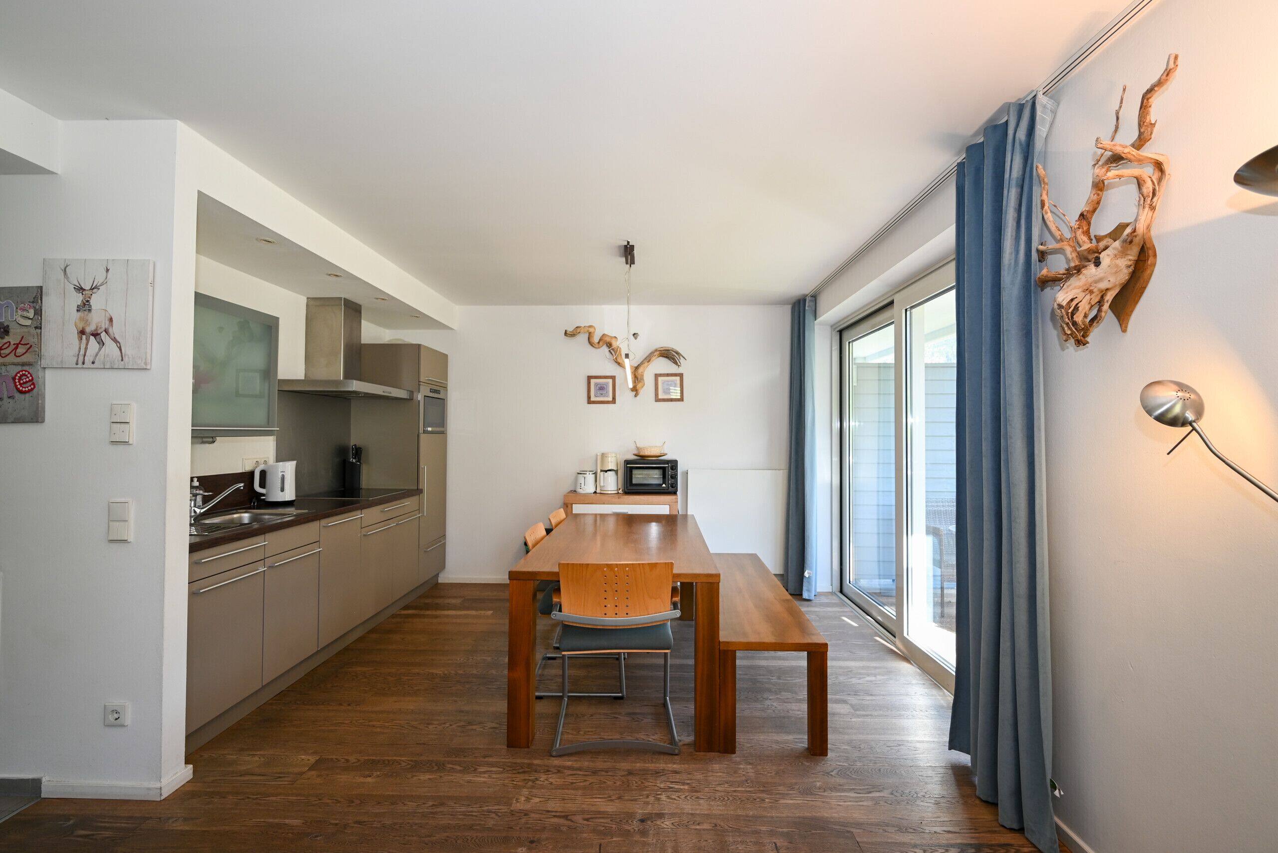 A modern kitchen with a dining table, chairs, and a view to the outside.
