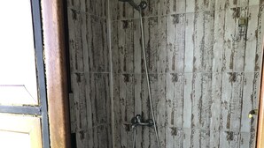 A shower with a wooden wall design, a metal showerhead, and a small step leading into the shower. - Eco-flat camping in mountain (Batumi)