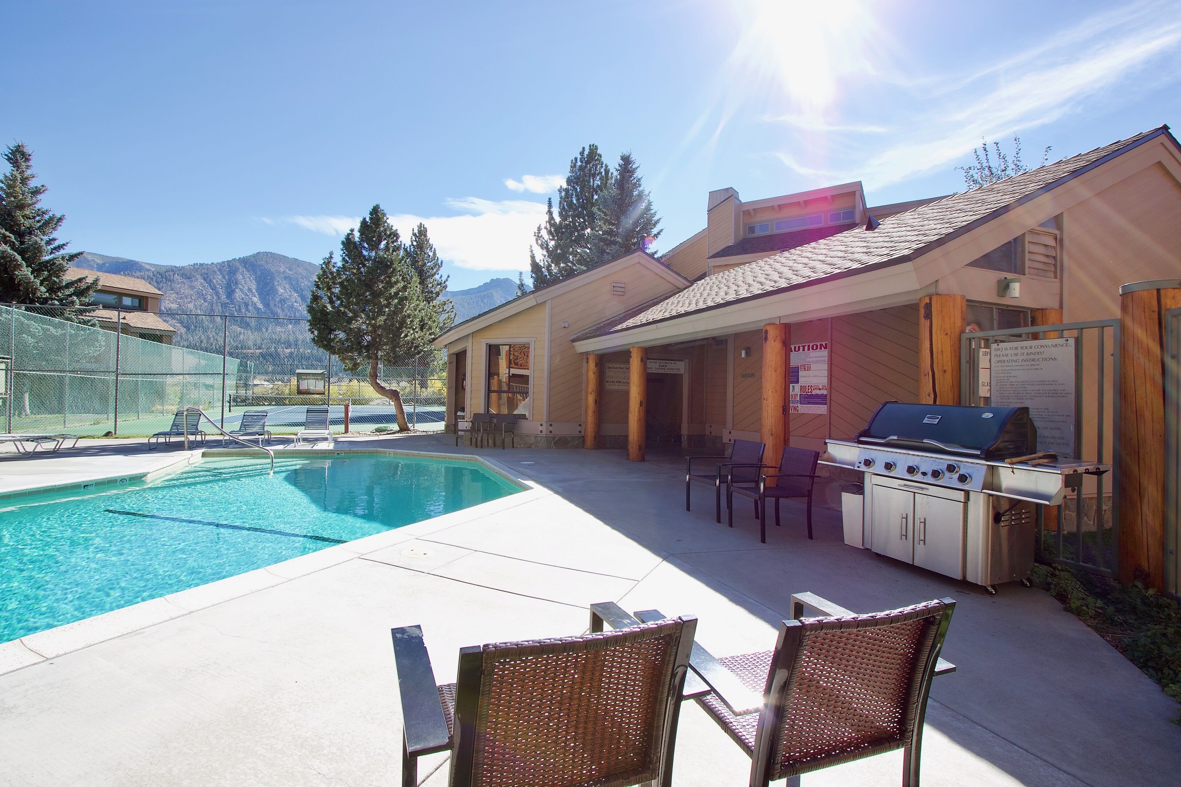 A backyard with a swimming pool, outdoor grill, and lounge chairs.
