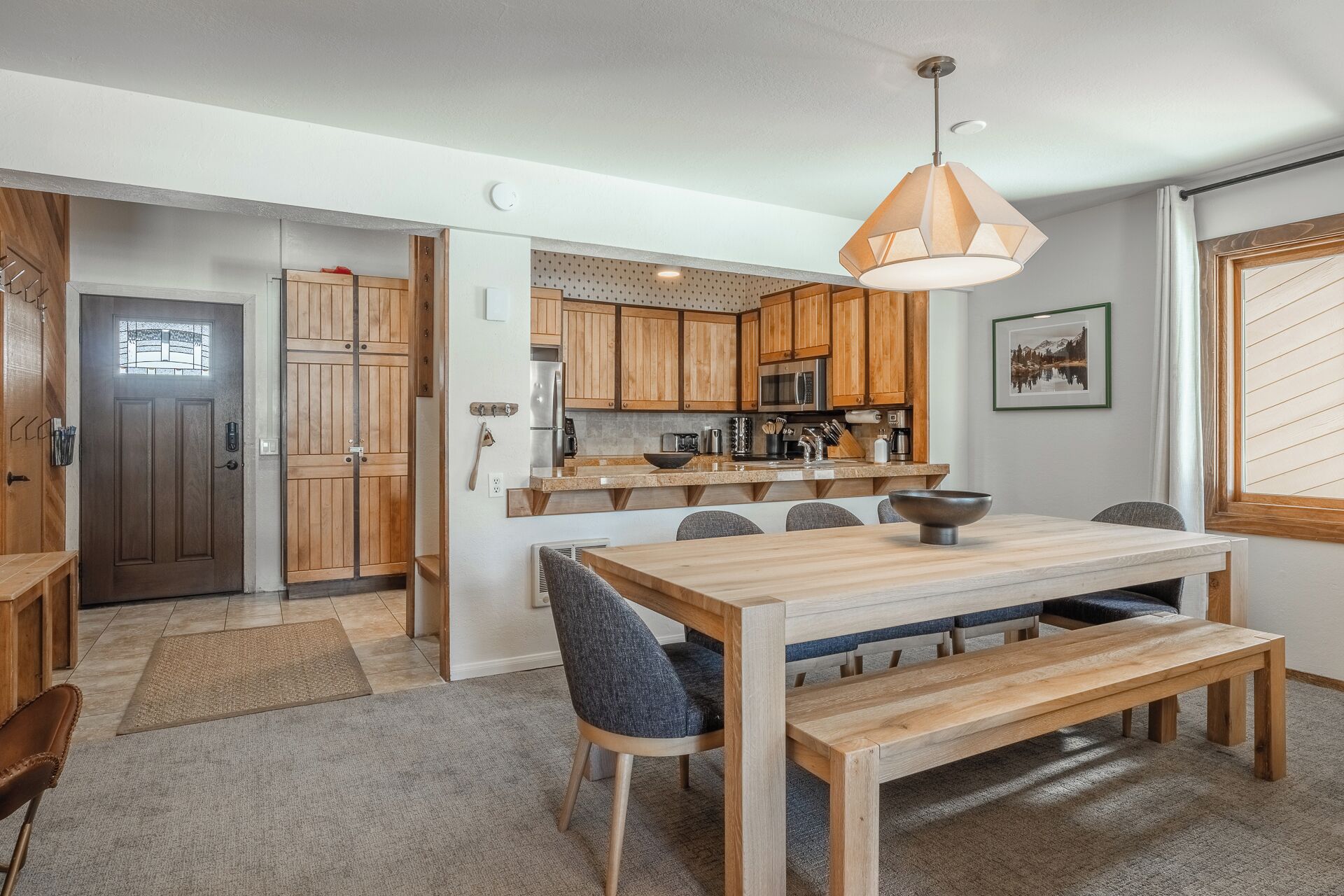 Una cocina moderna con armarios de madera, una isla central y una zona de comedor con banco.