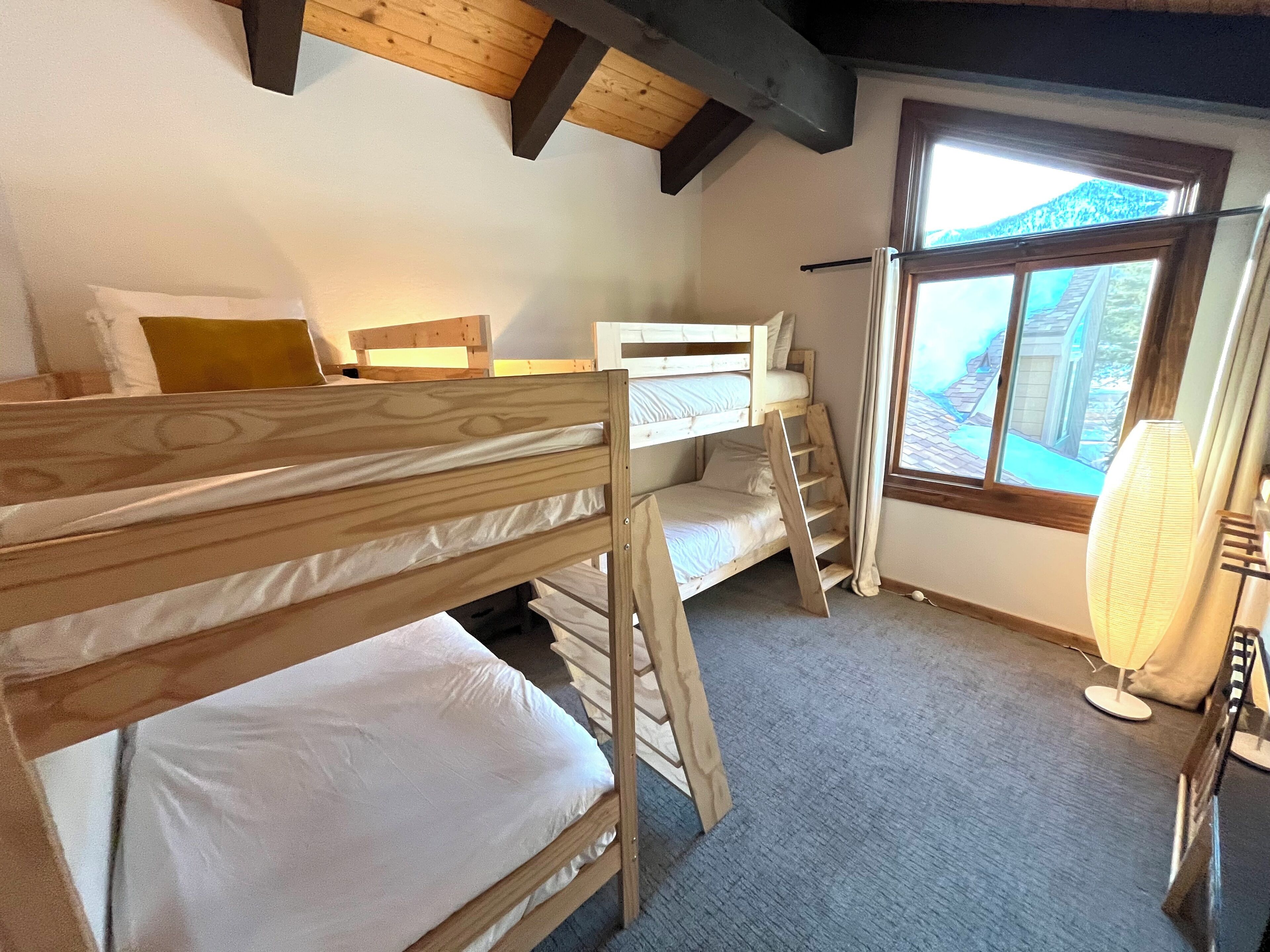 A bunk bed room with a window and a heater.