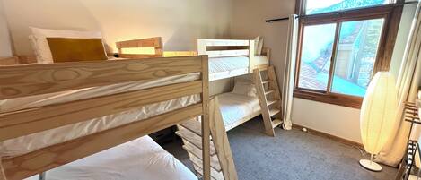 A bunk bed room with a window and a heater.