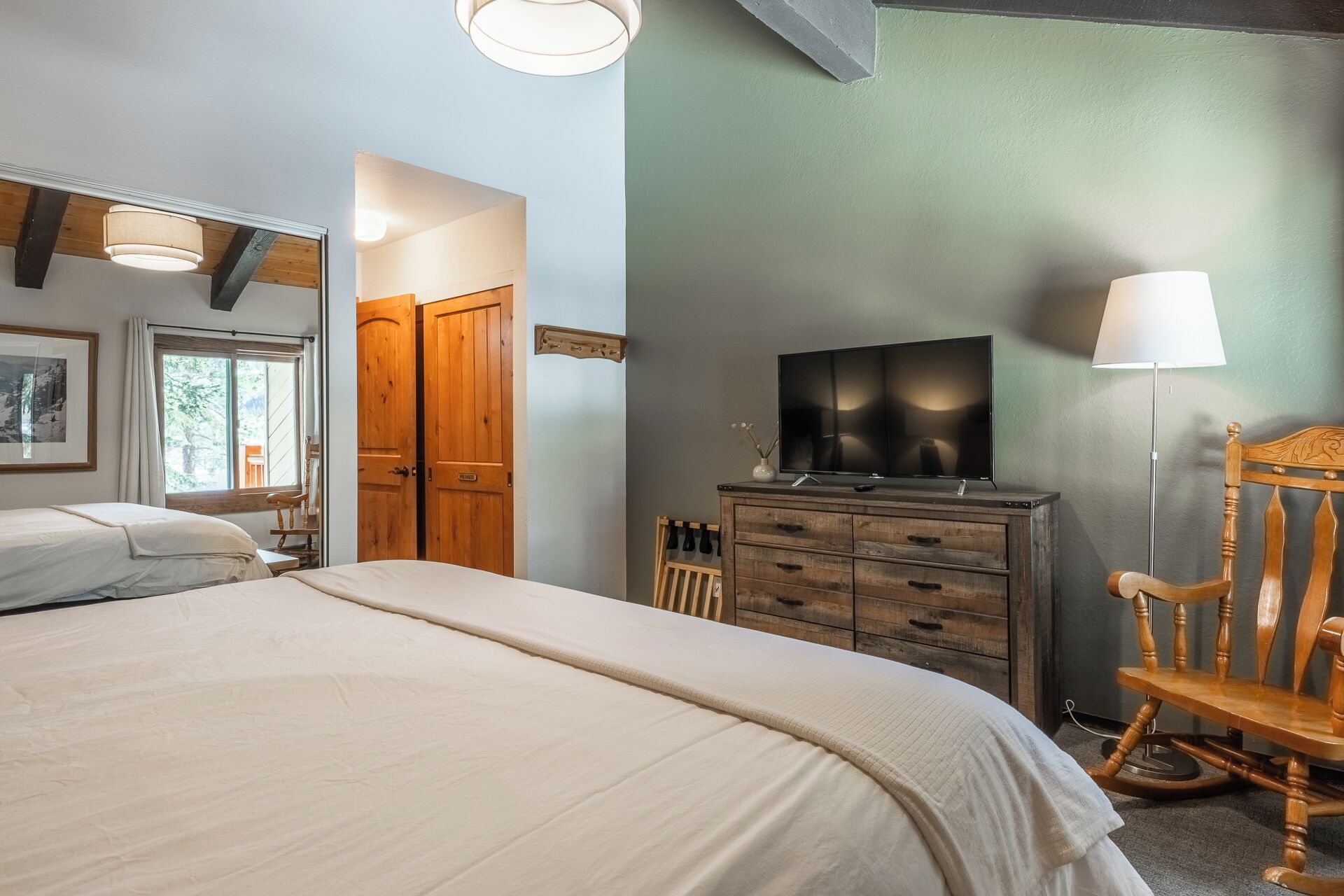 Ein Schlafzimmer mit einem großen Bett, einem Holzschrank und einem Fernseher auf einer Kommode.