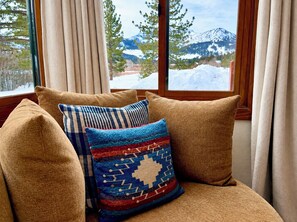 Ein gemütlicher Sitzbereich mit Blick auf schneebedeckte Berge durch ein Fenster.