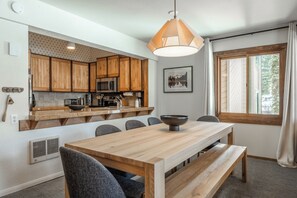 A modern kitchen with wooden cabinets, a built-in microwave, and a large window.